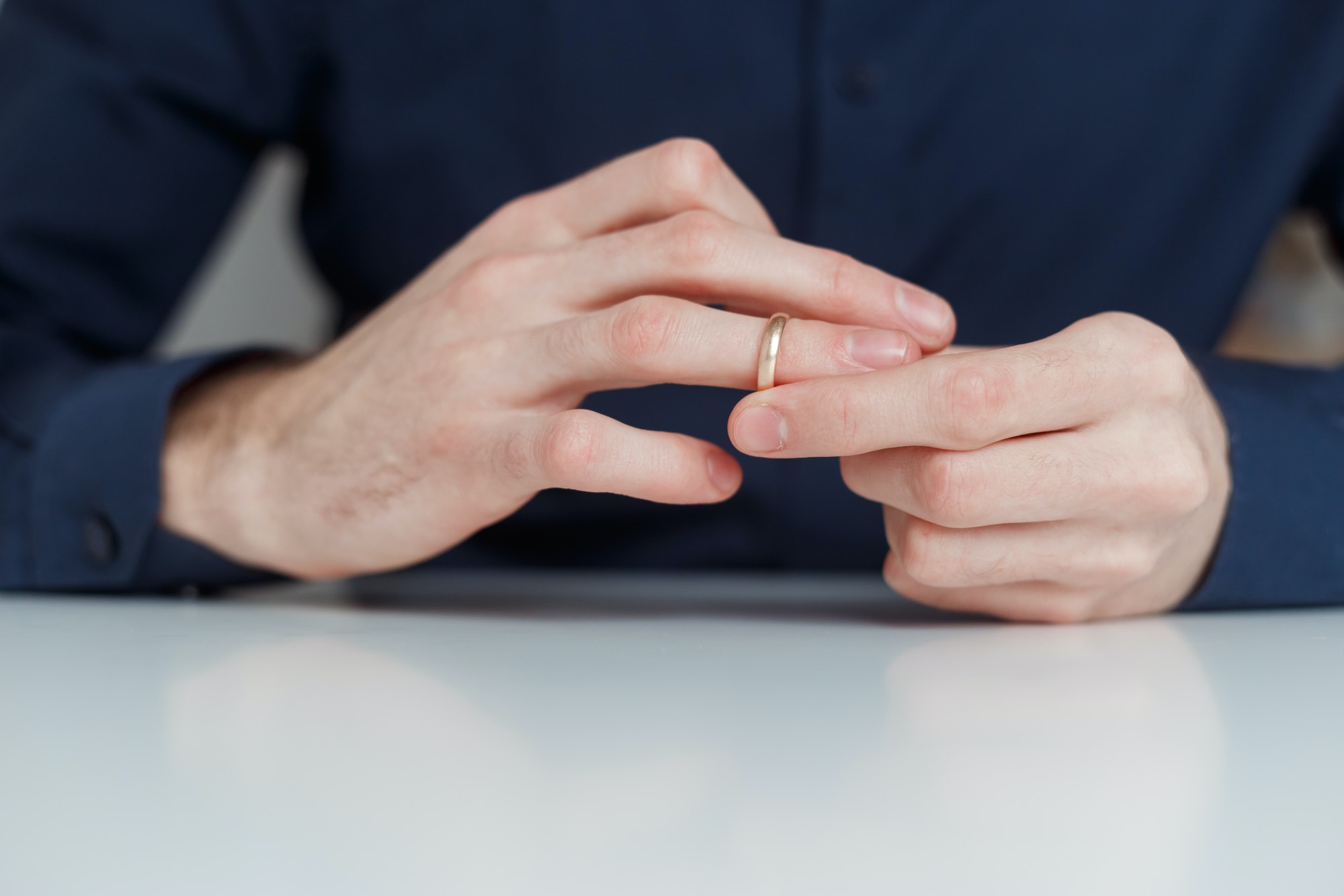 Young man is taking off the wedding ring. Close up view. Divorce concept
